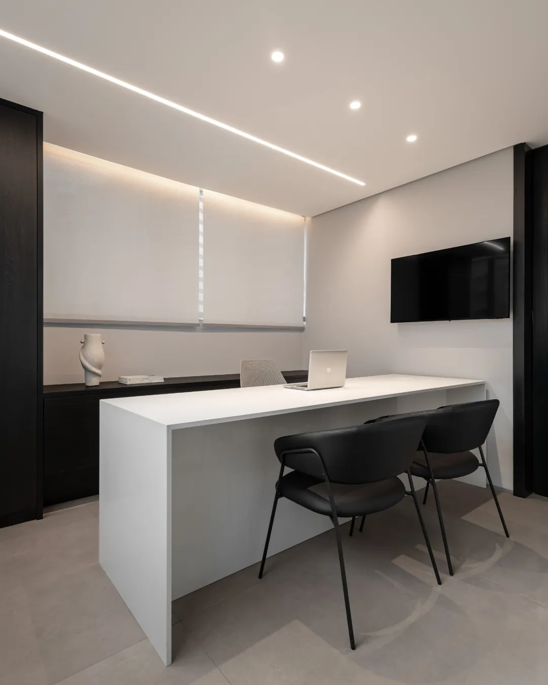 Consultório com mesa branca e cadeiras pretas