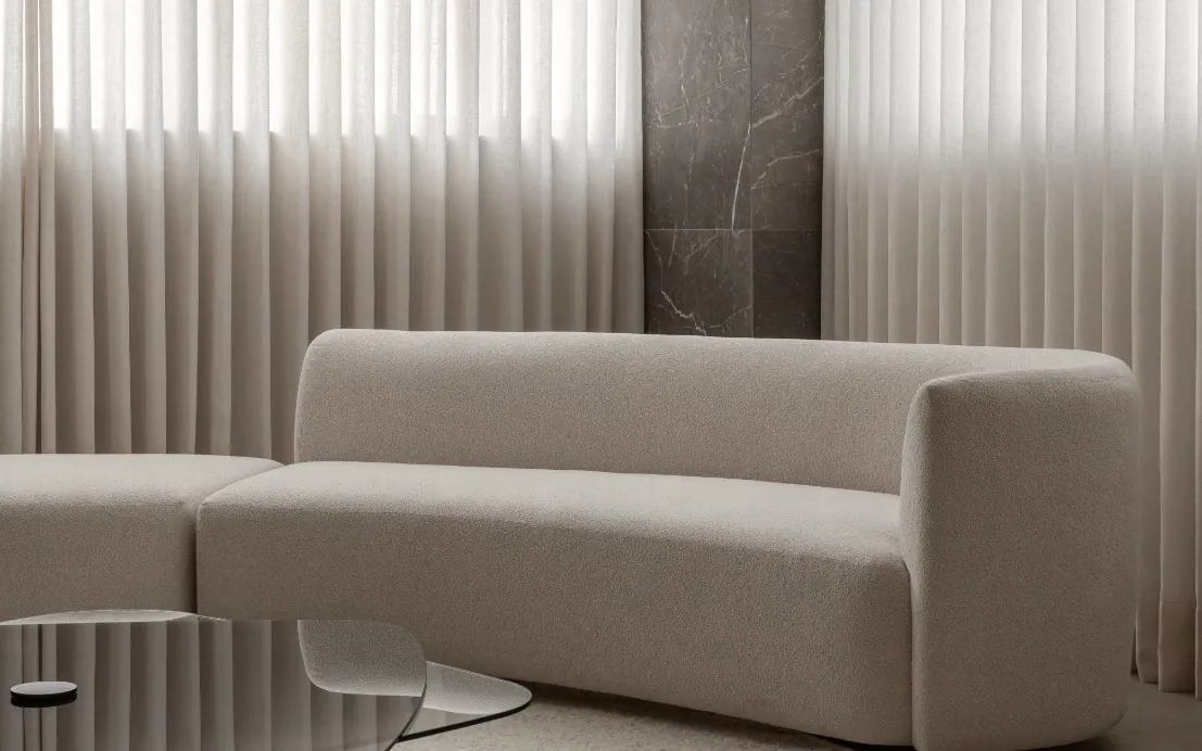 Sala de espera com sofá claro e cortinas de linho
